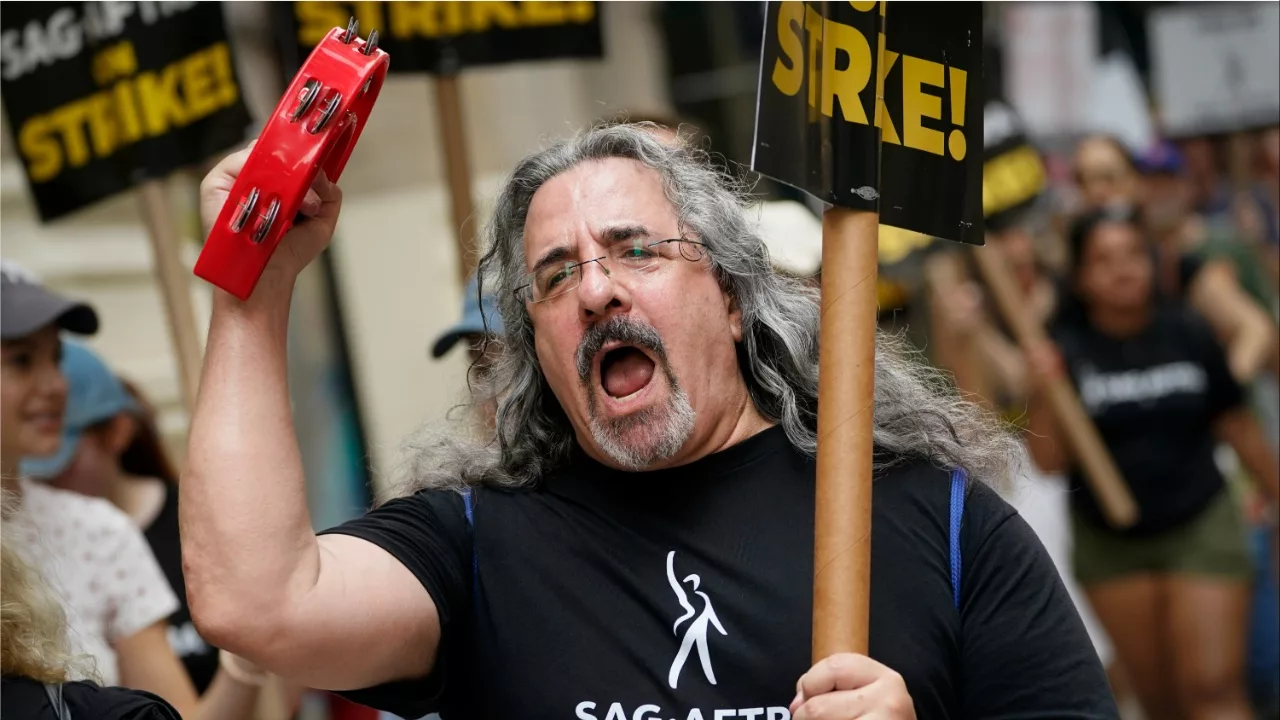Striking writers and actors chant as they walk a picket line. (Image: AP)